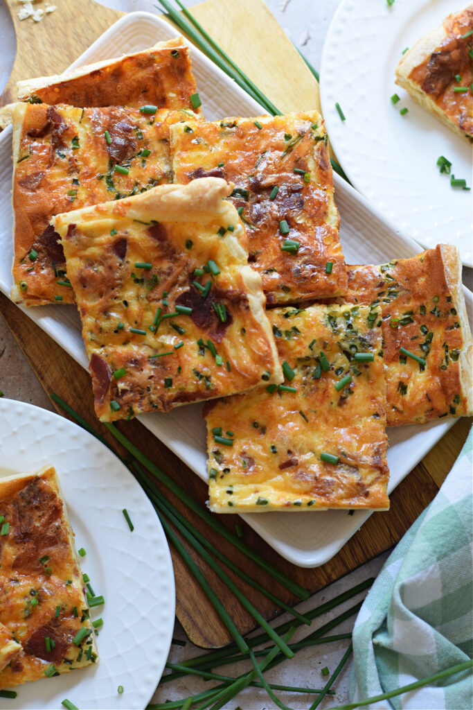 Puff pastry quiche on a white serving plate.