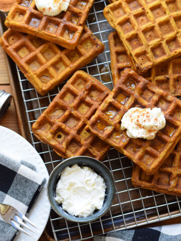 Pumpkin waffles on a baking tray with whipped cream.