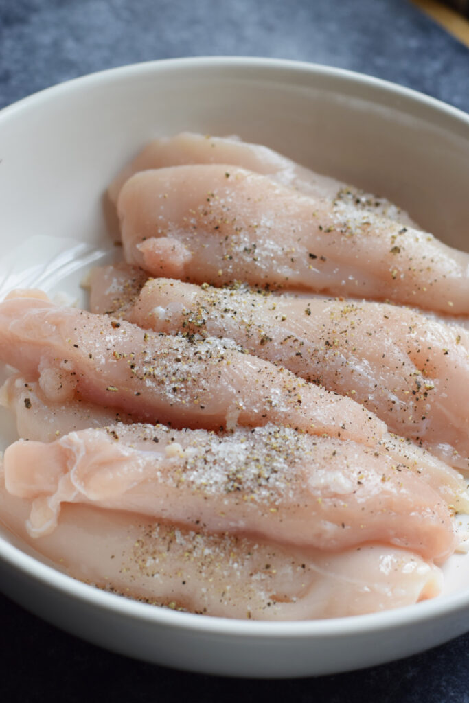 Seasoned chicken tenders in a bowl.