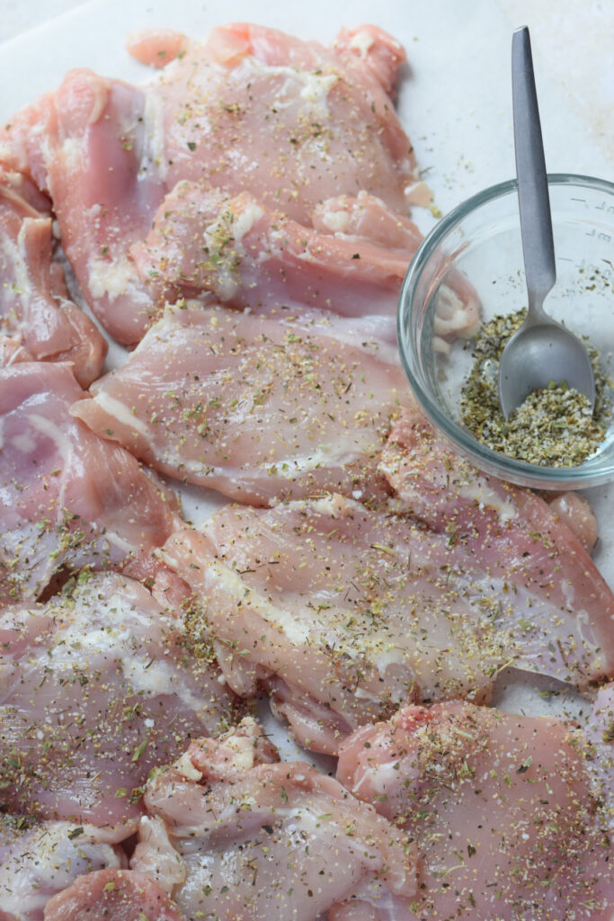 Seasoned chicken thighs on parchment paper.