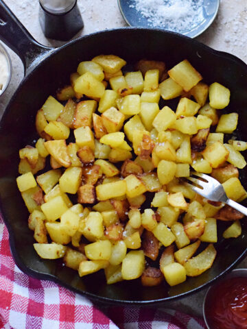 Fried cut potatoes in a skillet.