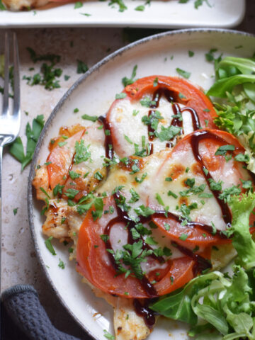 Close up of tomato mozzarella chicken on a skillet.