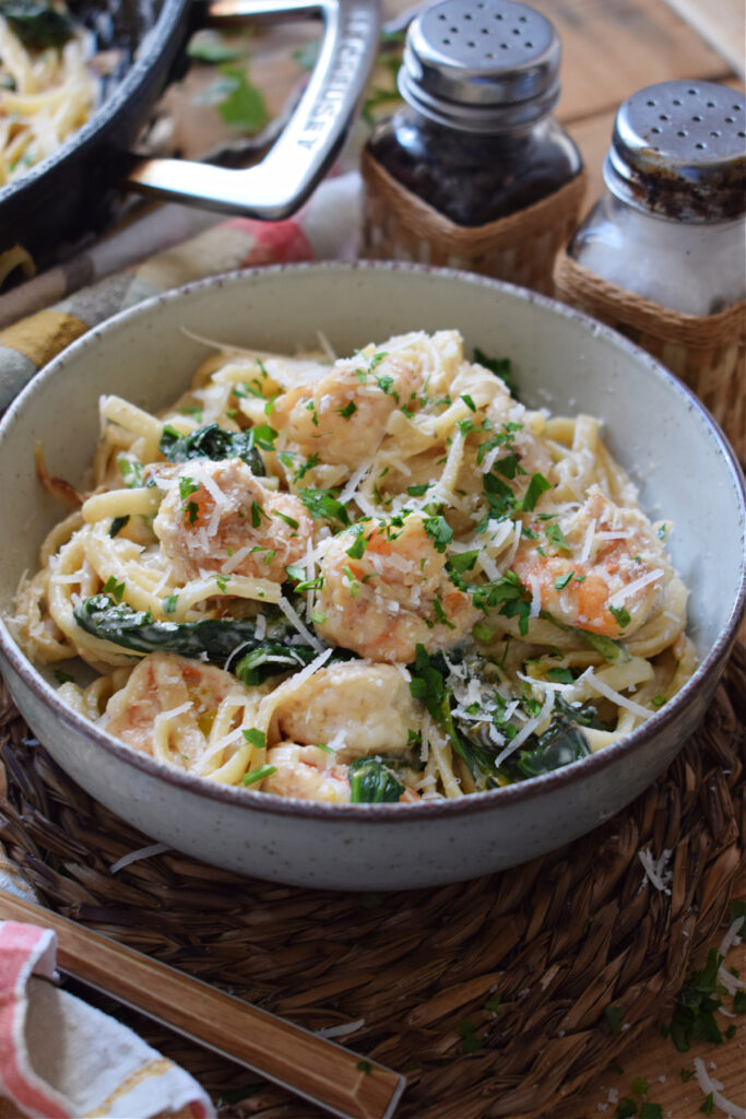 Creamy spaghetti in a bowl with shrimp and spinach.