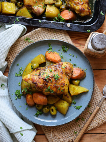 Moroccan chicken dinner on blue plate with a napkin and a fork.