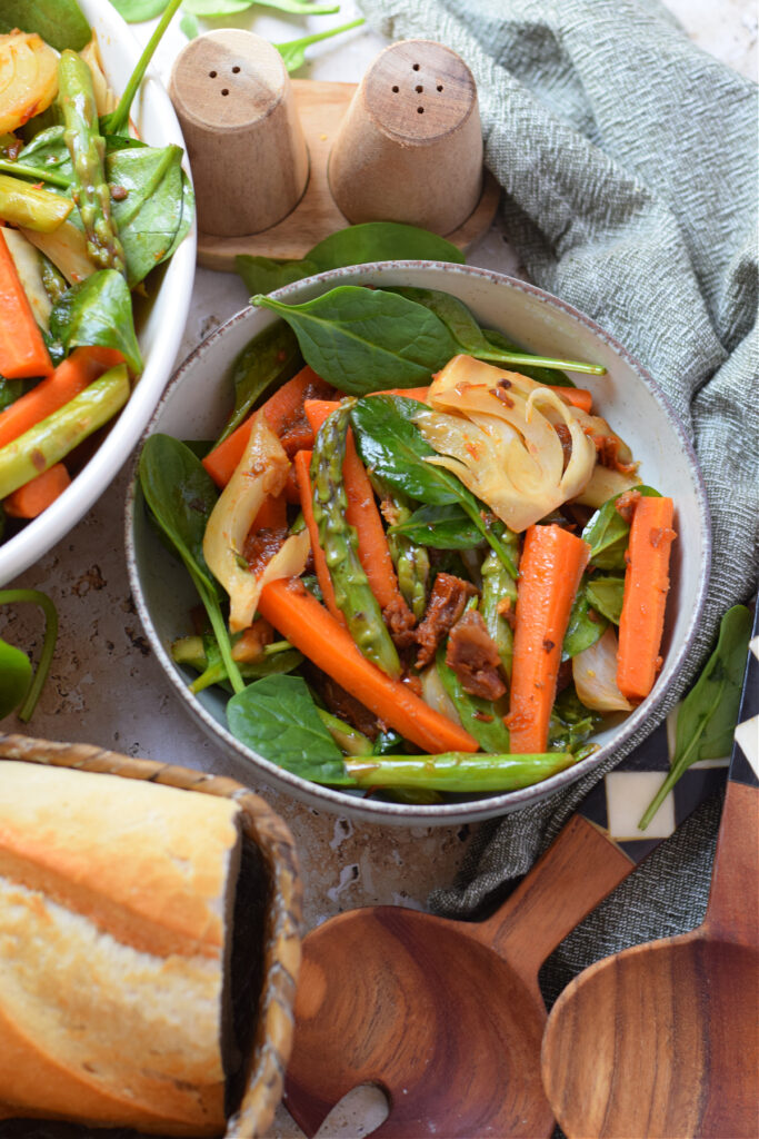 Spring vegetable stir fry in a serving bowl with bread on the side.
