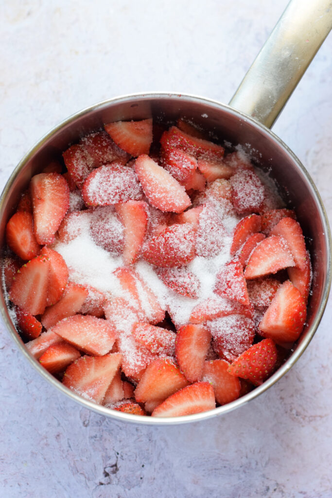 Sugar with strawberries in a saucepan.