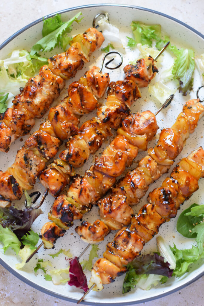 Chicken skewers on a white plate with lettuce.