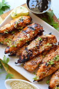 Chicken tenders in teriyaki sauce on a plate.