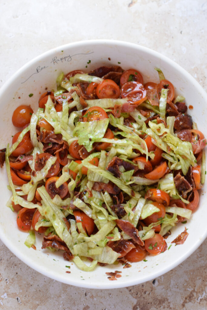 Tossed blt salad in a white bowl.