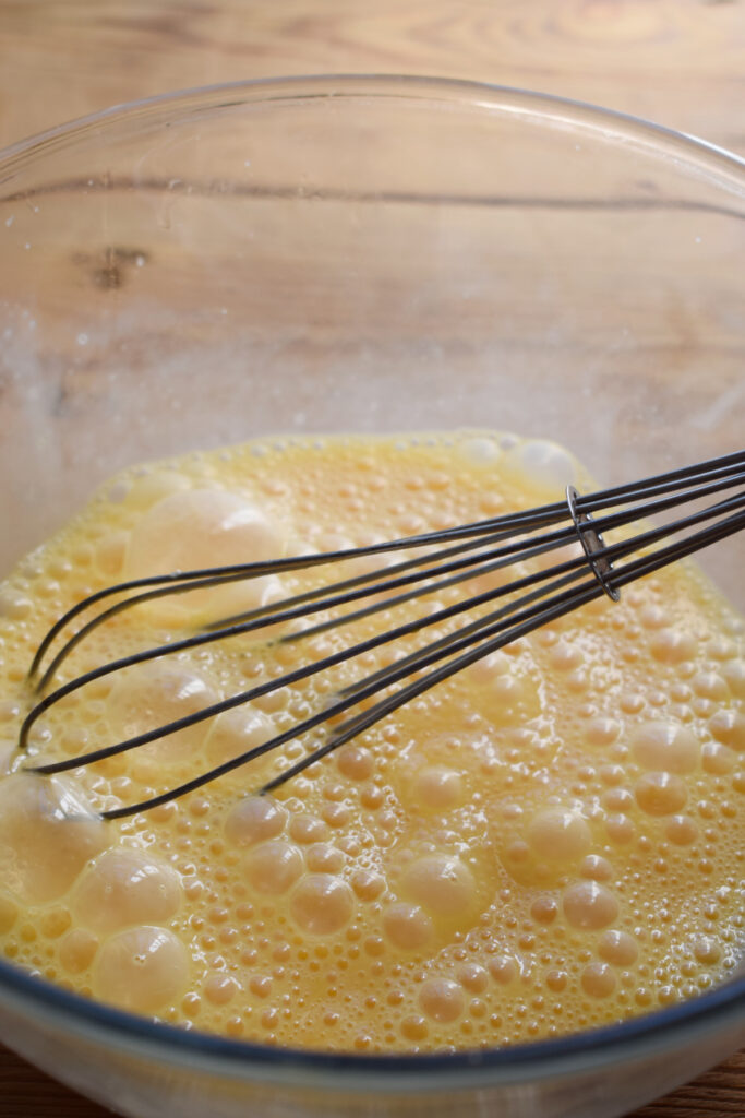 Whisked eggs in a glass bowl.