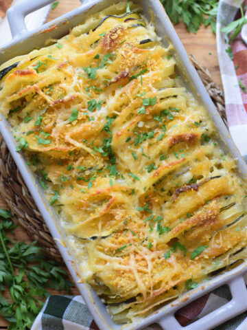 Potato zucchini gratin in a casserole dish with herbs.