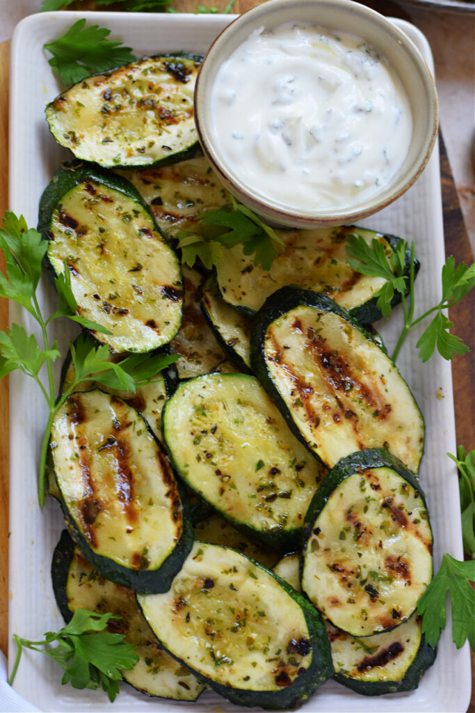 Grilled zucchini on a plate with a dip.