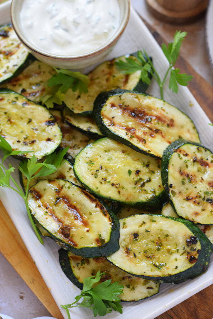 Close up of grilled zucchini with a yogurt dip.