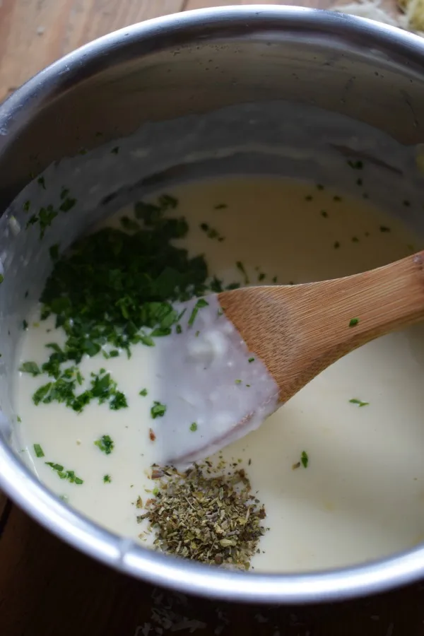 Adding seasonings to bechamel sauce in a saucepan.
